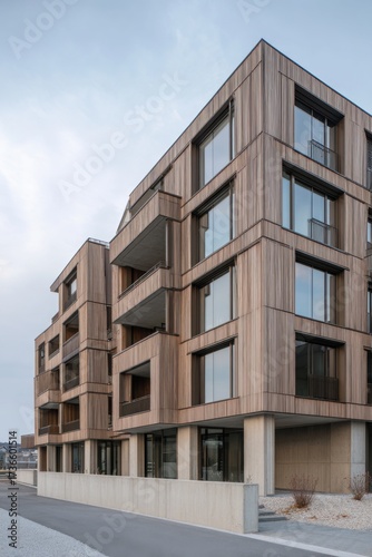 Modern wooden apartment building with large windows in an urban setting, showcasing contemporary architecture and sustainable design elements at dusk