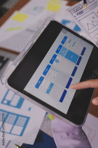 Close up ux developer and ui designer brainstorming about mobile app interface wireframe design on table with customer breif and color code at modern office.Creative digital development agency.
