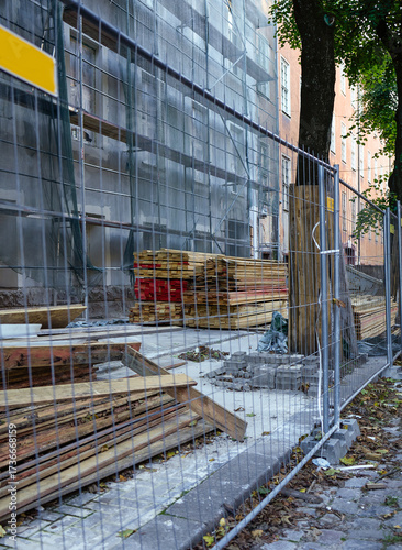 The building is fenced with a fence and a construction protective net, repair of the facade of the building. Construction and repair of buildings, restoration. Scaffolding, roof repair boards