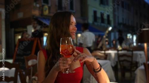 Woman in red dress with Aperol Spritz evening restaurant Venice