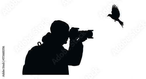 Silhouette of photographer capturing a bird in flight against a bright sky