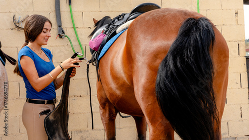Girl caring for horse in equestrian center setting