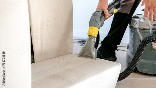 Man cleaning sofa with ionized water machine at home
