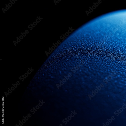 Close-up of a textured blue surface with a gradient, evoking depth and detail against a dark background.