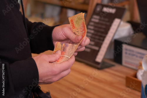 Close-Up of Hands Counting Argentine Peso Bills