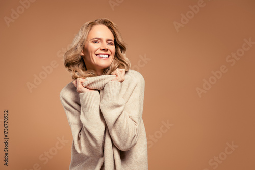 Charming mature woman with radiant smile wearing elegant sweater showcasing blonde hairstyle