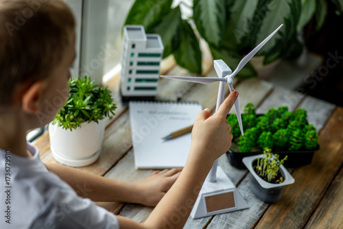 Primary school scientific environmental project. Concept of ecology lessons, ecological awareness of children. Little kid making design of future city with renewable energy, wind turbine, green spaces