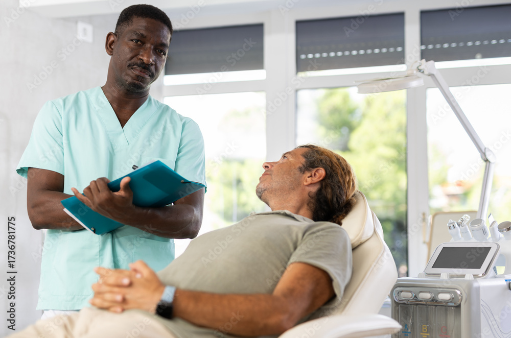 Fototapeta premium Cosmetic doctor discusses treatment options and reviews documents with patient using folder.