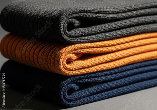 Stack of folded cozy knit socks in dark gray orange and navy blue