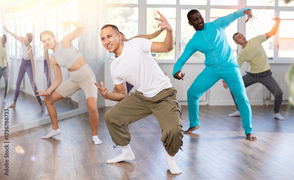 Naklejka premium Young happy guy and international dancers preparing their modern dance at light dance studio
