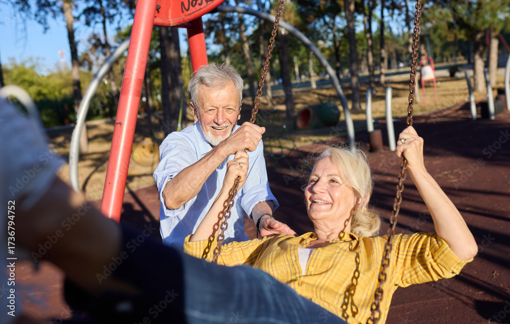 Obraz premium Happy active senior woman having fun on a swing in park outdoors