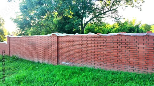 View of the newly completed red brick wall. New brick wall made of red bricks. Concept of building construction and construction site.