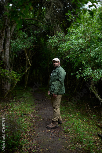 Man walking along a nature trail surrounded by vegetation turns to look at the camera. El Palmar National Park, Argentina. Concepts: ecotourism, traveling to connect with nature