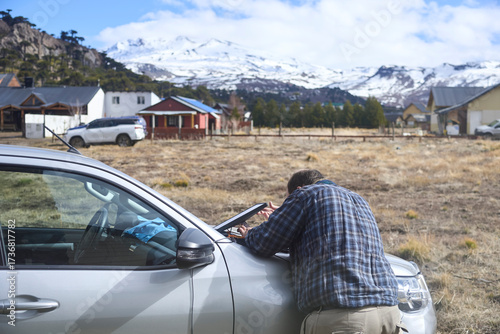 Traveler positioning a satellite internet receiver antenna on the front of his car to get a signal and connect to the network. Current technology allows to stay connected from even remote locations.