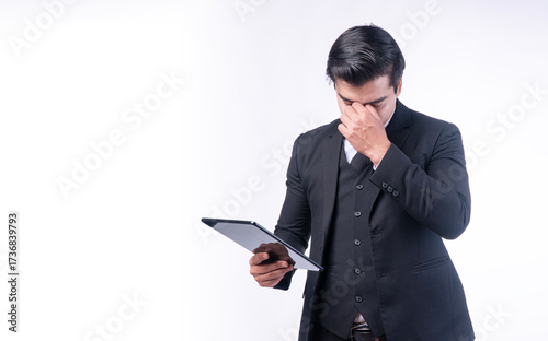 Stressed businessman in formal suit holding tablet with worried expression, symbolizing corporate pressure, financial stress, decision making, and modern workplace challenges.
