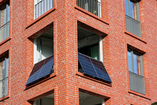 Wide balcony on red brick facade fitted with solar panels shows a german balcony power plant