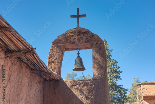 Bell and a cross in a construction made of adobe