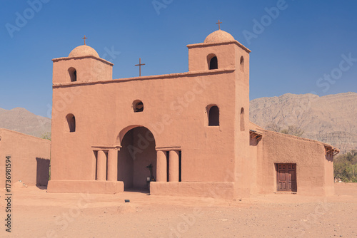 Historic adobe church with twin bell towers against mountains