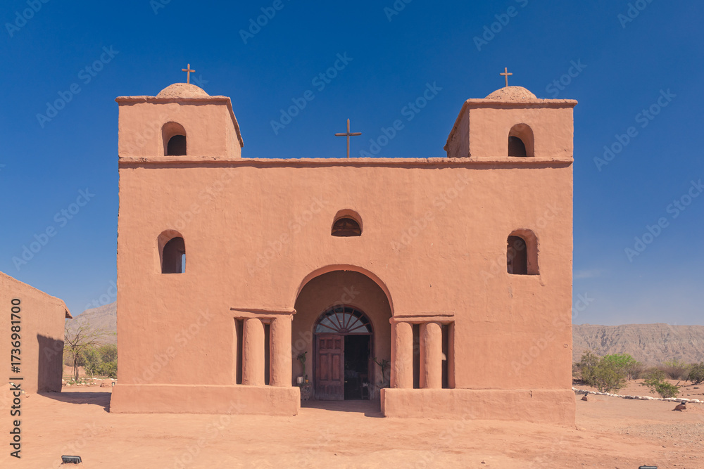 Fototapeta premium Historic adobe church with twin bell towers against mountains