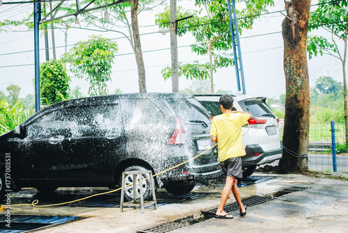 A car wash worker washing a car at a car wash station.