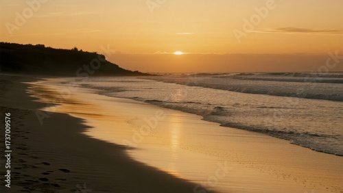 Sunset over a tranquil beach with golden light reflecting on wet sand and gentle waves
