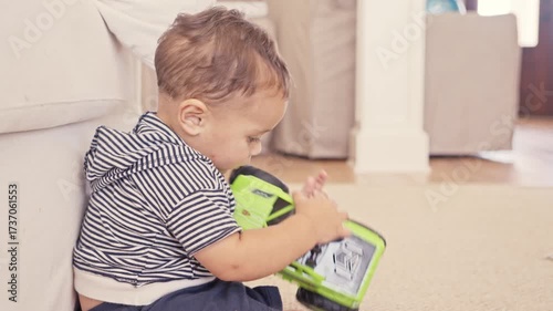 Baby Playing with Green Toy Truck on Floor Indoors