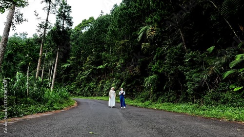 Wallpaper Mural Two Muslim Asian women walking on a quiet highway with trees around the road. Bathing forest. Torontodigital.ca