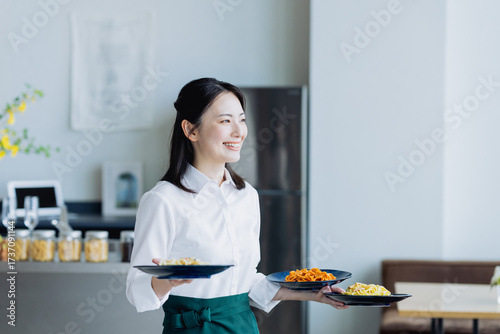 カフェで料理を運ぶ若い女性の店員