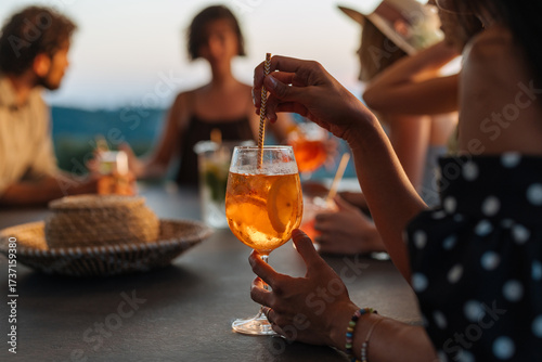 Photography Woman holding aperitif cocktail at sunset party with friends