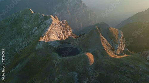 Drone video of the alpine lake Drakolimni Tymfis surrounded by mountain peaks at sunrise. Stunning natural scenery perfect for travel, adventure, and documentary projects.