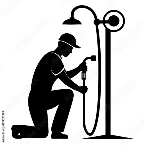 Plumber kneeling and working on a shower fixture silhouette