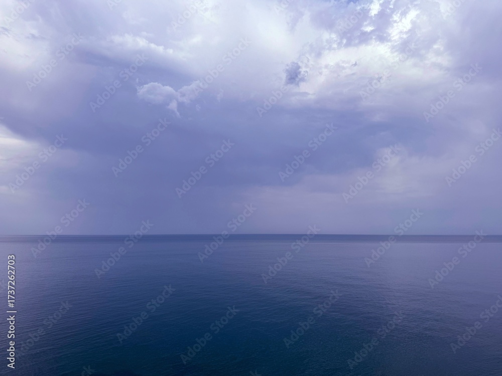 Fototapeta premium Overcast sky clouds over calm ocean.