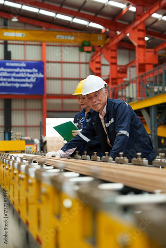 Engineers and staff inspect the production line of components in a metal sheet and metal roofing manufacturing plant.