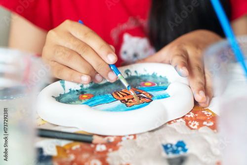 Child Painting a Colorful Plate with Watercolors