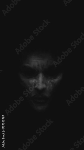 Dark mysterious ghostly face emerging from shadows with a haunting expression.