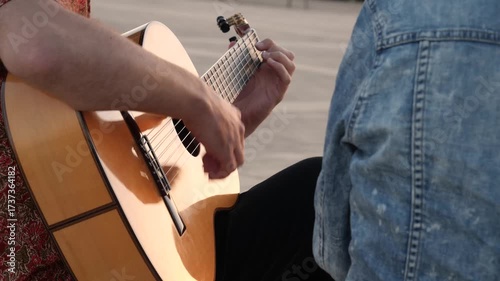 Close up shot of a street musician playing a classical Spanish guitar. His skilled fingers strumming the strings creating a vibrant flamenco rhythm