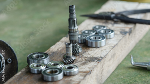 A collection of metal ball bearings and bevel gears laid out on a worn wooden surface, likely in a workshop or repair setting. 
