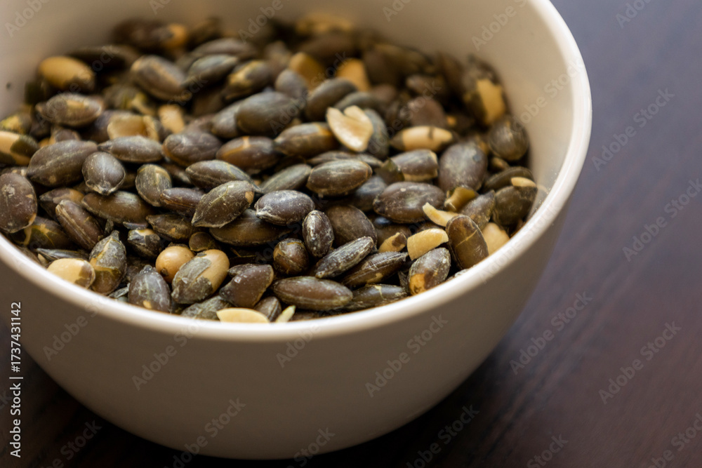 Fototapeta premium baked salted pumpkin seeds in a small white bowl