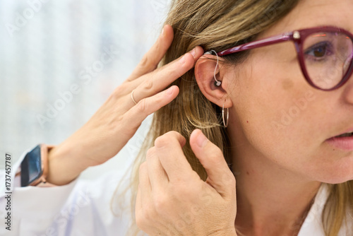 Tablou pe pânză Woman adjusting modern hearing aid on her ear