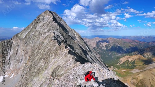 Hiking Capitol Peak Wilderness Knifes Edge North East Ridge Trail scrambling rock climbing Rocky Mountains Colorado 14er boulders summer blue sky morning sunny rugged terrain pan left