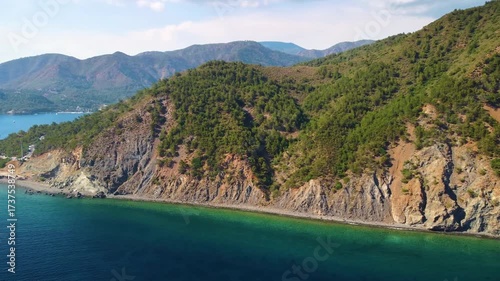 aerial perspective captures the tranquil beauty of Adasi Island's rugged coastline, lush green hills, and the crystal clear turquoise waters of the Mediterranean Sea in Turkey. Perfect for travel, nat