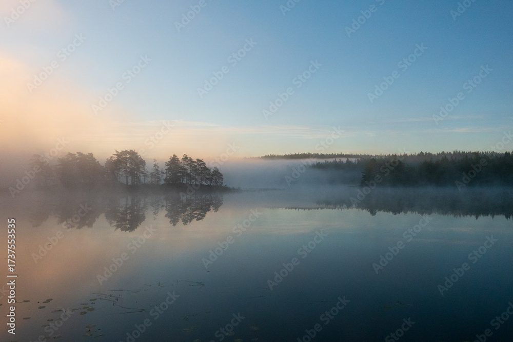 Fototapeta premium Sunrise over a misty lake, a peaceful and mysterious landscape