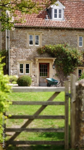 A house with a green wheelbarrow in front of it. The house is old and has a red roof