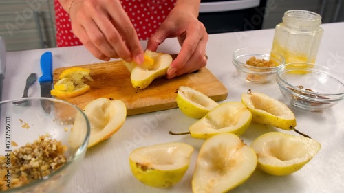 Pastry chef woman hands smearing halved pears with lemon cooking dessert. Cuisine culinary prepare cook dish domestic food recipe ingredients. Healthy nutrition eating fresh citrus products fruit.