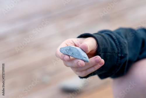 Teenager's hand holding broken pebble. Blue pebble in hand with textured pattern of break