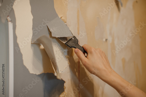 Hand scraping old wallpaper off wall