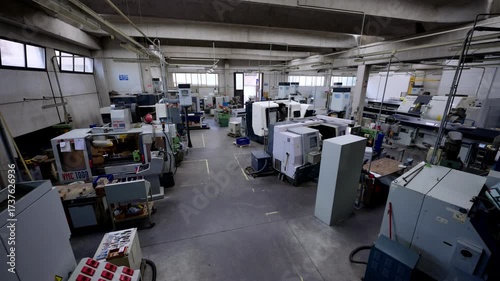 Wide shot of a clean, modern machine shop or manufacturing factory floor with several CNC machines, highlighting high-tech automation and precision engineering