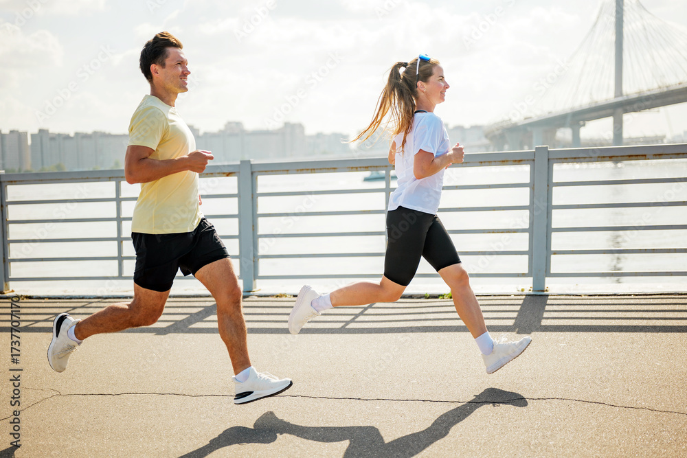Fototapeta premium Running along the riverside with friends during a sunny afternoon workout