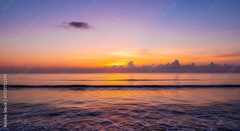 Fototapeta premium Vivid Sunset Sky Over Calm Ocean Water and Gentle Shoreline A stunning, low-angle seascape capturing the vibrant, colorful beauty of sunrise or sunset over the ocean 