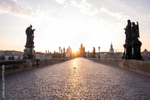 Stunning sunrise over Prague with warm golden light illuminating historic architecture, cobblestone streets, and iconic city landmarks in high-quality detail.